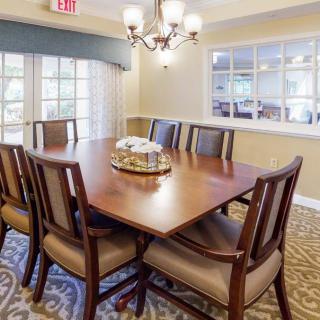 A well-lit dining or meeting room with a wooden table and chairs arranged neatly around it.
