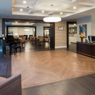 A modern hotel lobby with a reception desk, seating area, and piano.