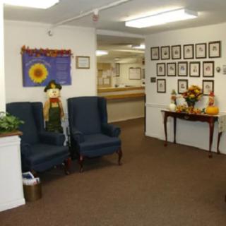 A cozy waiting room with blue chairs, autumn-themed decorations, and framed pictures on the wall.