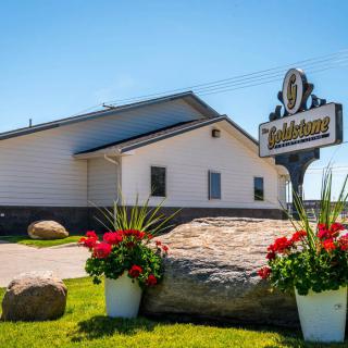 A restaurant exterior with a sign and flower arrangements in the foreground on a sunny day.