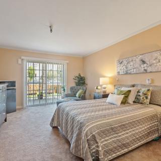 A cozy bedroom with a comfortable bed, soft lighting, and a large window providing natural light.