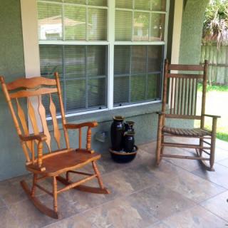 Two wooden rocking chairs on a porch, next to a window, offering a peaceful spot for relaxation.