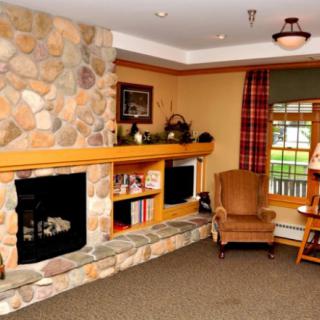 Cozy living room with a stone fireplace and armchair, featuring warm decor.