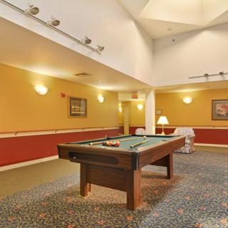 A cozy game room with a pool table under warm lighting.