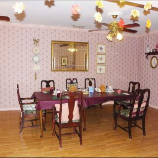 A traditional dining room with a large table, chairs, wallpaper, and decorative items.