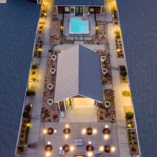 A beautifully lit rooftop area with a pool and seating, viewed from above during the evening.