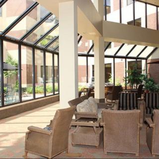 A bright atrium with comfortable seating, featuring large glass windows allowing ample natural light.