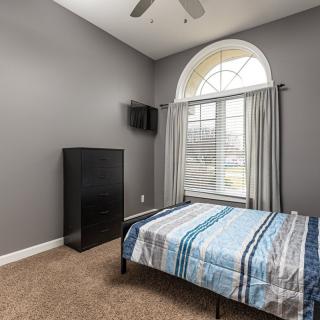 A modern bedroom with a large window, featuring a bed and minimalistic furniture.