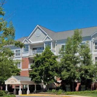 A multi-story residential building surrounded by trees under a clear blue sky.