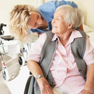 A caregiver is providing assistance to an elderly person in a wheelchair.