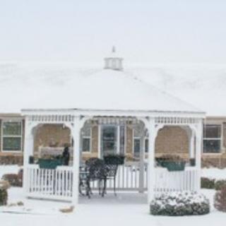 A snow-covered gazebo with outdoor furniture.
