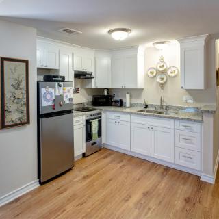 A modern kitchen with white cabinets, stainless steel appliances, and wood flooring.