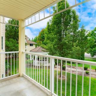 A balcony with a view of lush green trees and surrounding buildings.