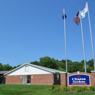 The exterior view of Clinton Gardens, featuring flags against a clear blue sky.
