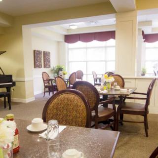 A cozy dining area with tables, chairs, and a piano in the corner.