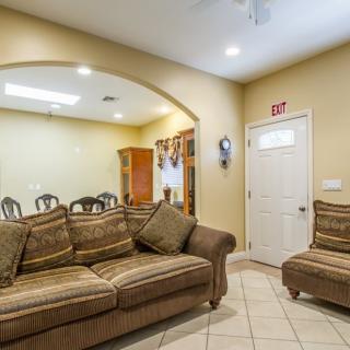 A cozy living room with a couch and armchair, adjacent to a dining area through an archway.