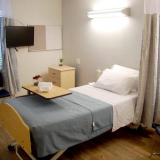 A clean and organized hospital room with a single bed and modern amenities.