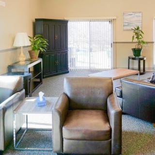 A cozy lounge area featuring comfortable seating, decorative plants, and ample natural light.