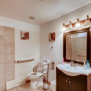 A modern bathroom with a sink, mirror, and toilet, featuring tiled flooring and a well-lit interior.