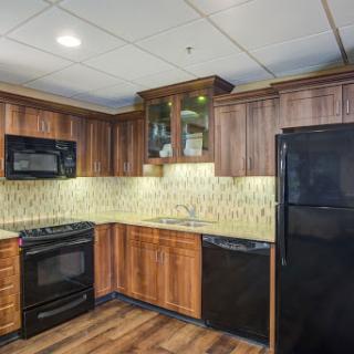 A contemporary kitchen featuring wooden cabinets and black appliances, with a stylish tile backsplash.