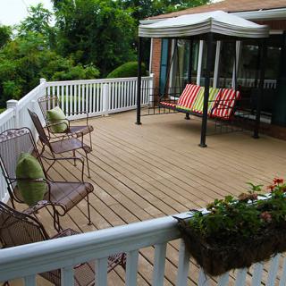 An inviting outdoor deck with cozy seating, a canopy for shade, and potted plants for decoration.