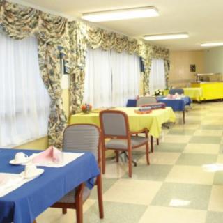 A neatly arranged dining area with tables and chairs, featuring colorful tablecloths and decorative curtains.