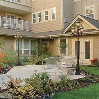 A serene courtyard with a landscaped garden, featuring a residential building in the background.