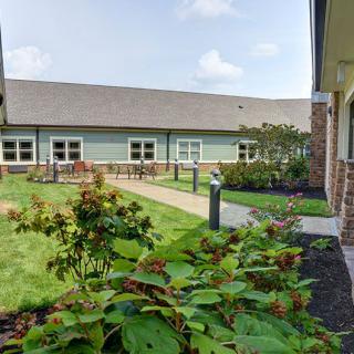A well-maintained courtyard garden with blooming flowers and a building in the background.