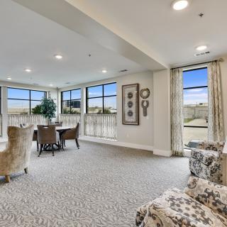 A spacious and elegantly decorated living room with a dining area, featuring large windows that allow ample natural light.