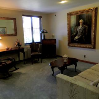 A traditional living room with a portrait on the wall and classic furniture.