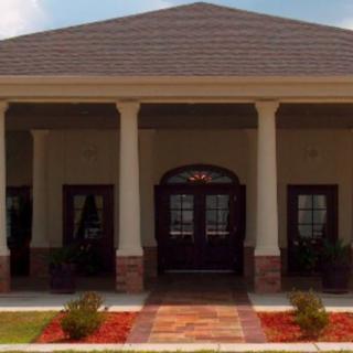 A building entrance with columns, a triangular roof, and landscaped surroundings.