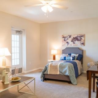 A cozy bedroom with a neatly made bed, soft lighting from lamps, and tasteful decor.
