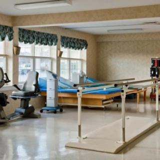 A rehabilitation room equipped with exercise machines and parallel bars for physical therapy.