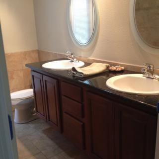 A modern bathroom featuring a double sink vanity with mirrors and a toilet.
