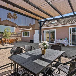 A sunny backyard patio with a pergola, featuring a dining table and chairs.