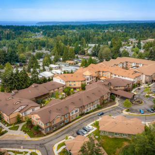 Aerial view of a large building complex surrounded by greenery in a suburban area.