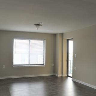 An empty room with a window and door, featuring hardwood floors.