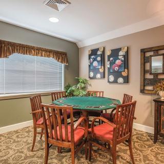 A cozy dining area with a round table and wooden chairs, adorned with wall art and a corner plant.