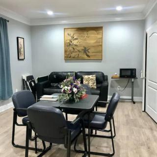 A cozy living room with a dining area featuring a table, chairs, sofa, and decorative elements like flowers and paintings.