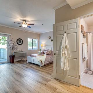 A modern bedroom with wood flooring, natural light, and an adjoining bathroom.