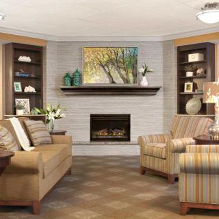 A cozy living room with a fireplace, flanked by bookshelves and furnished with sofas and armchairs in warm tones.