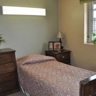 A small bedroom with a single bed and wooden furniture.