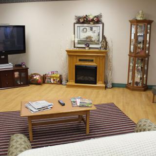 A cozy living room featuring a fireplace, television, and a coffee table with magazines.