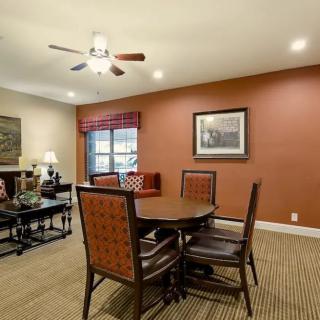 A cozy living room with a dining area, featuring a round table and chairs, a ceiling fan, and warm earth-tone walls.