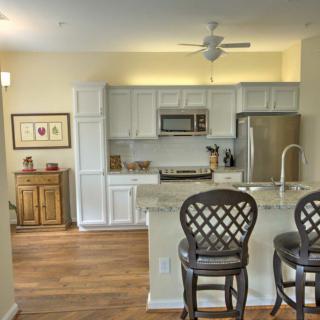 Modern kitchen with bar stools and stainless steel appliances.