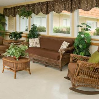 A cozy living room with wicker furniture and lush indoor plants, basking in natural light.