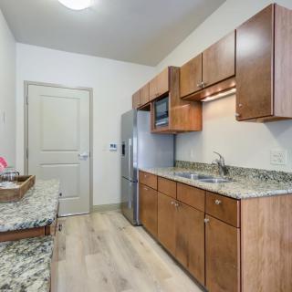 A modern kitchen with wood cabinets, granite countertops, and stainless steel appliances.