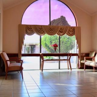 A spacious lobby area with large arched windows, elegant curtains, and comfortable seating around a table adorned with flowers.