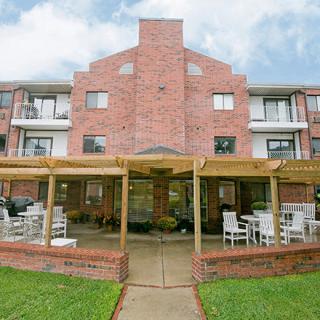 A brick apartment building with an outdoor patio and seating area.