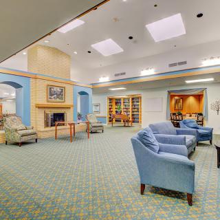 A cozy lounge area featuring comfortable seating and a fireplace, with a small library section.